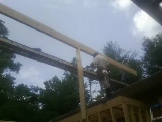 Carpenter setting a ridge beam over a new addition frame — Ice Dam Removal by Roofing Brothers in Conesville