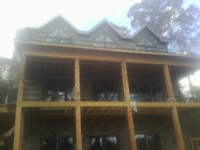 Dormers and porch framing on a large log home under construction — Roof Coating work by our crew in Conesville